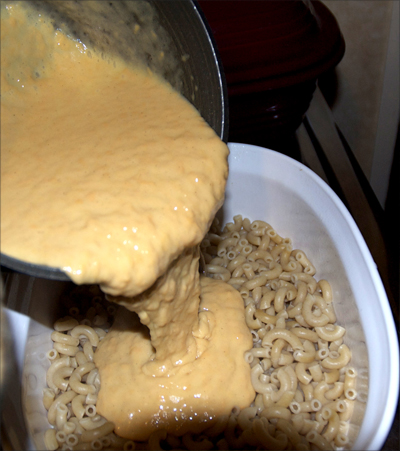 pouring Daiya over macaroni